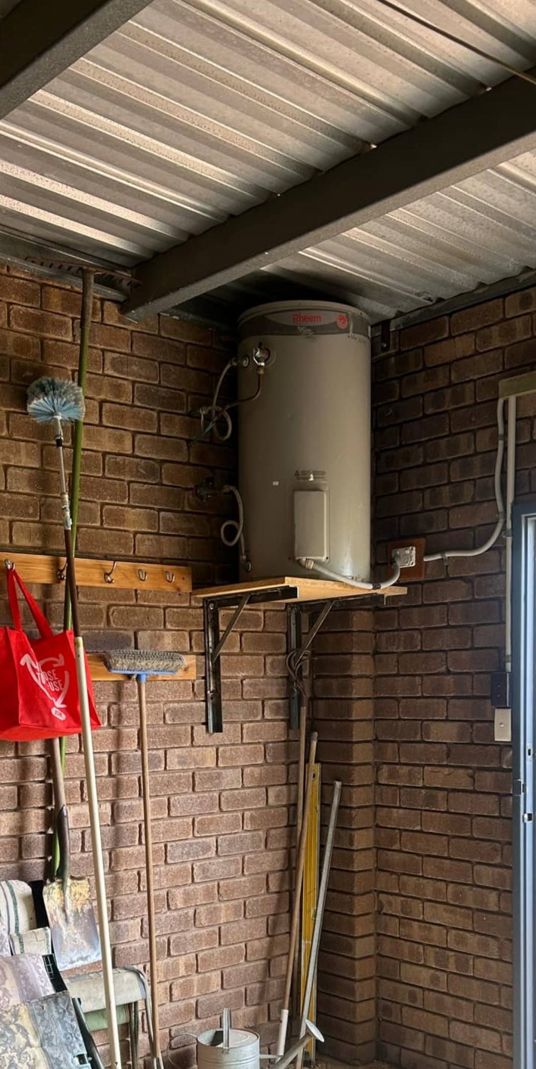 An old electric storage hot water unit in a carport, due for an upgrade
