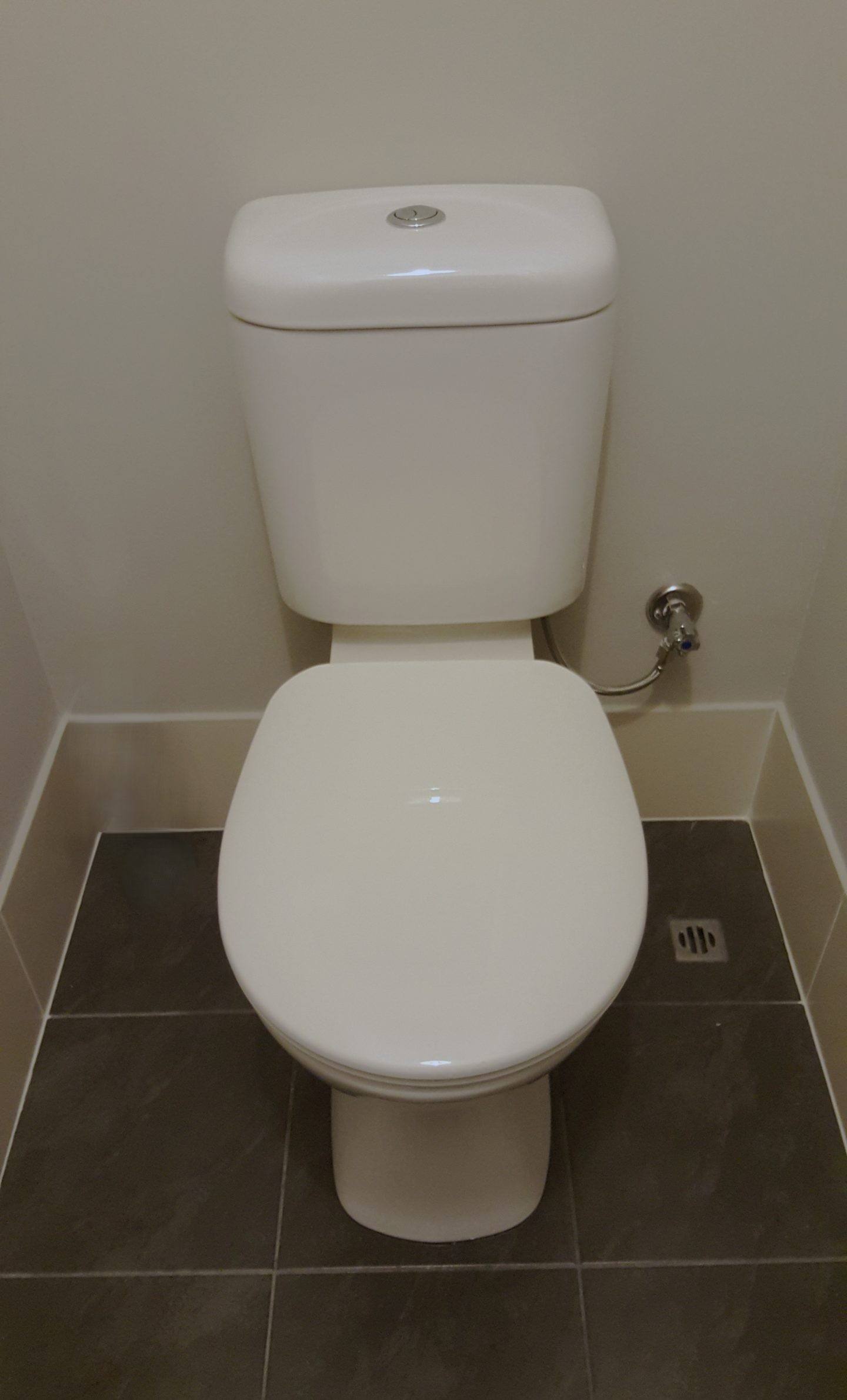 A new close-coupled toilet installed on dark floor tiles