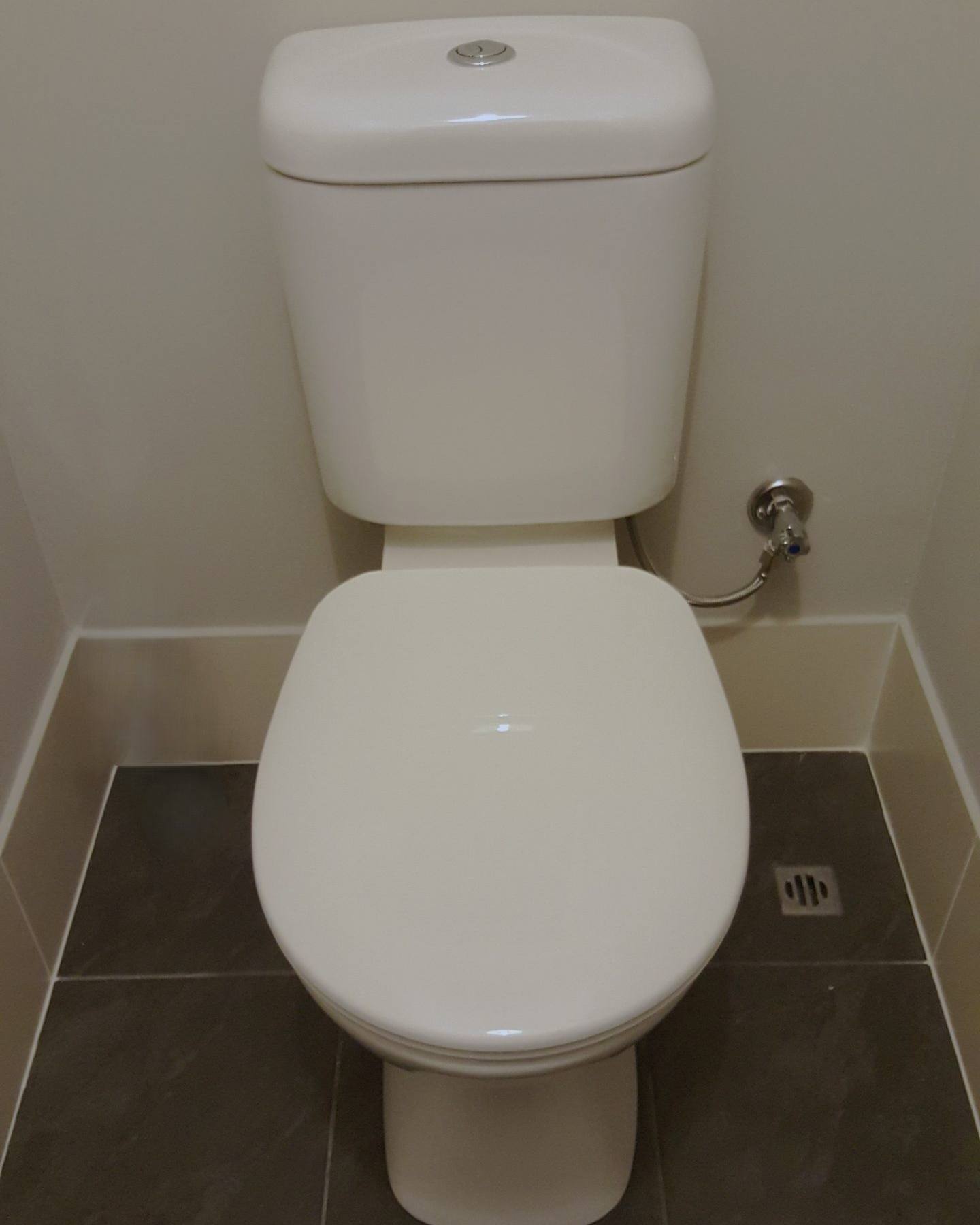 A new close-coupled toilet installed on dark floor tiles