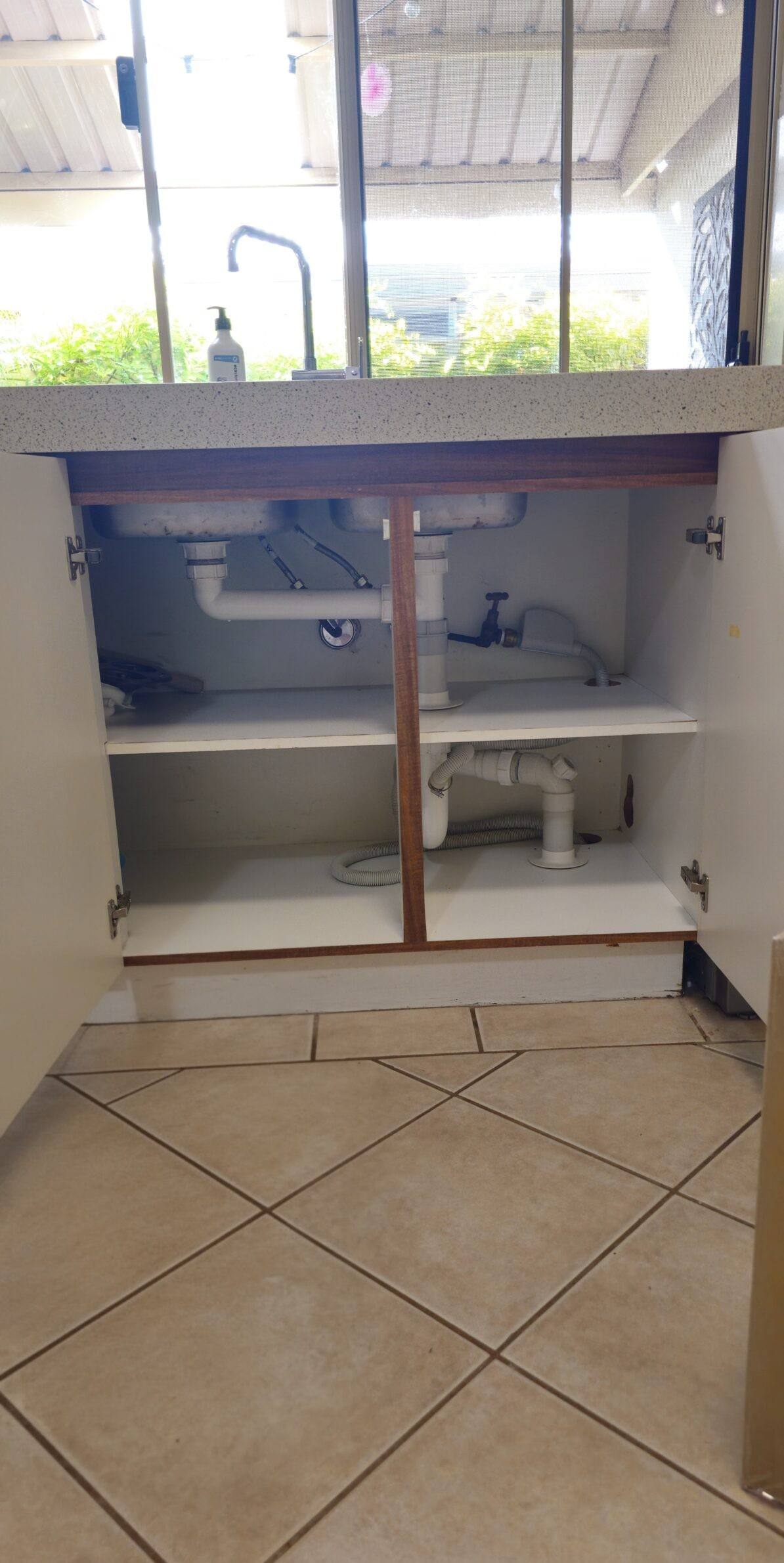 An under-sink water filter installed in an outdoor kitchen cupboard