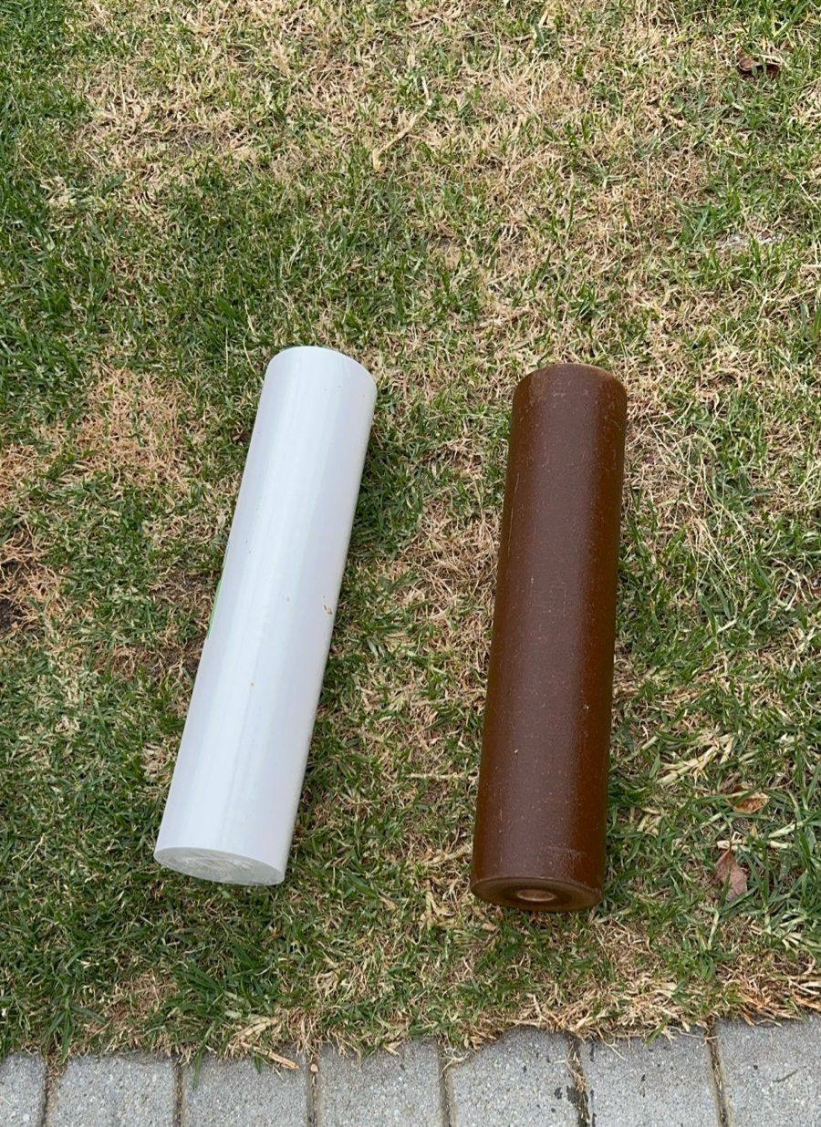 A new white filter cartridge beside a used brown one on the lawn